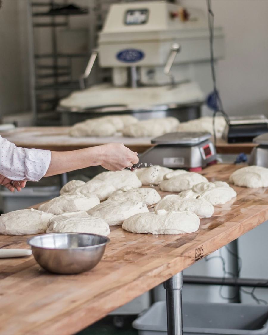 Baker shaping dough on a workbench in a bakery kitchen