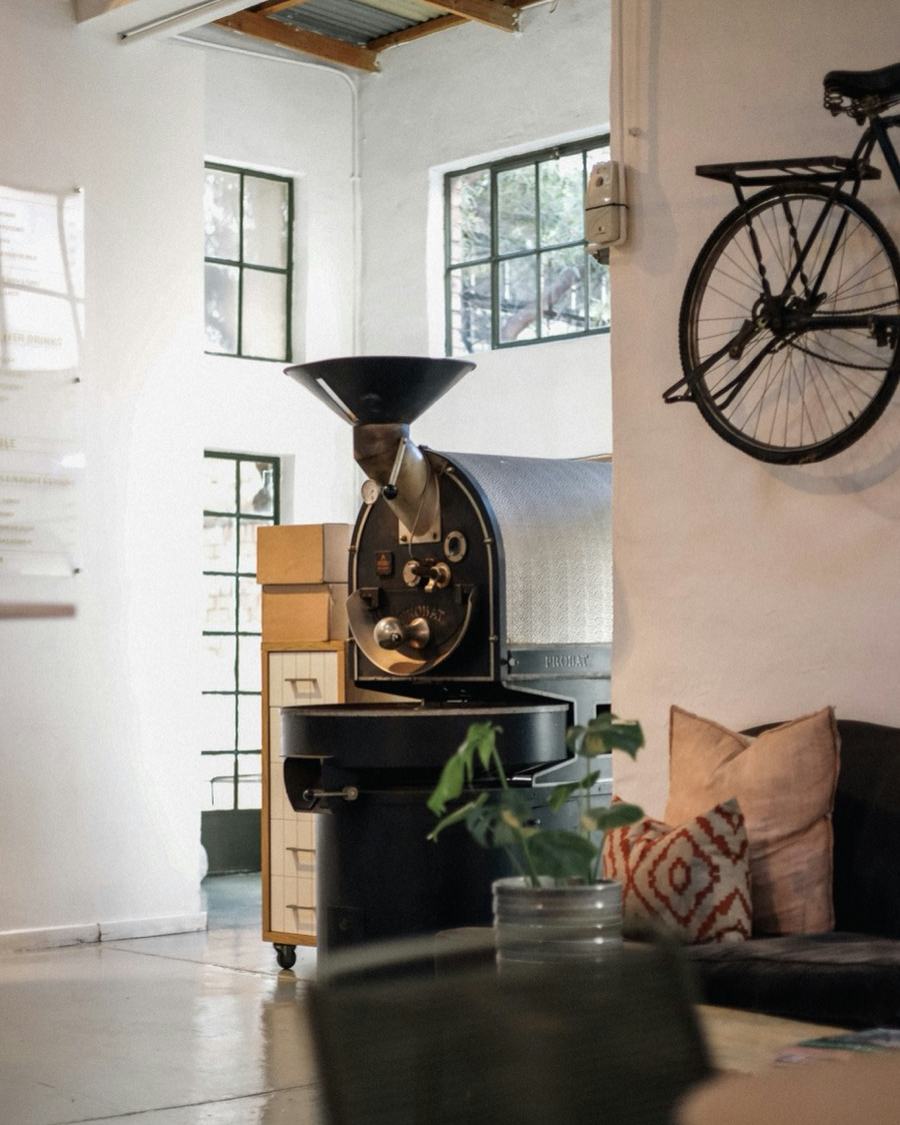 Small roastery with a drum roaster and a bicycle on the wall